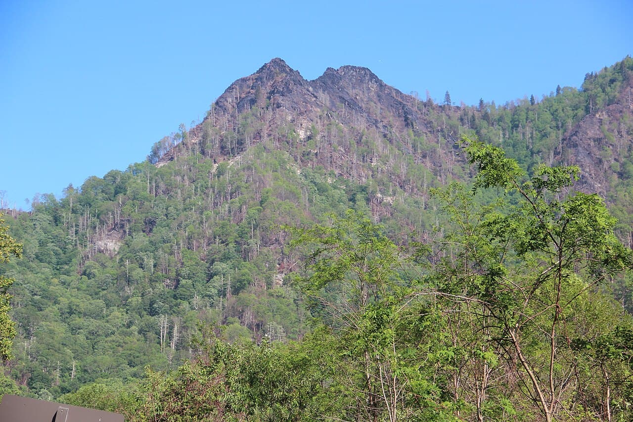The twin rocky pinnacles of the Chimney Tops rising above forested ridges in the Great Smoky Mountains