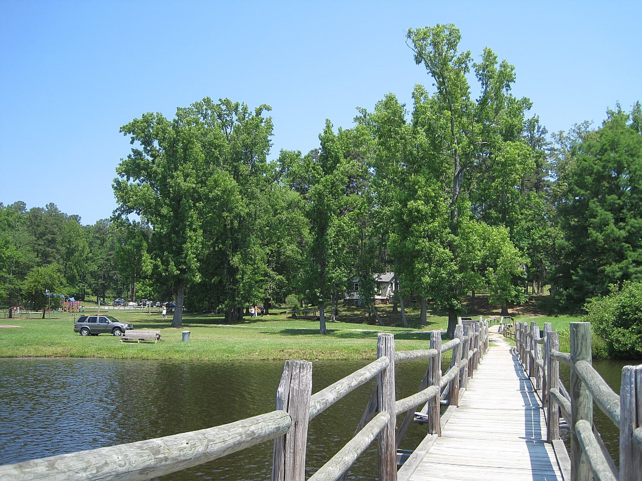 The wooden footbridge crossing Lake Placid toward the day-use lawn at Chickasaw State Park