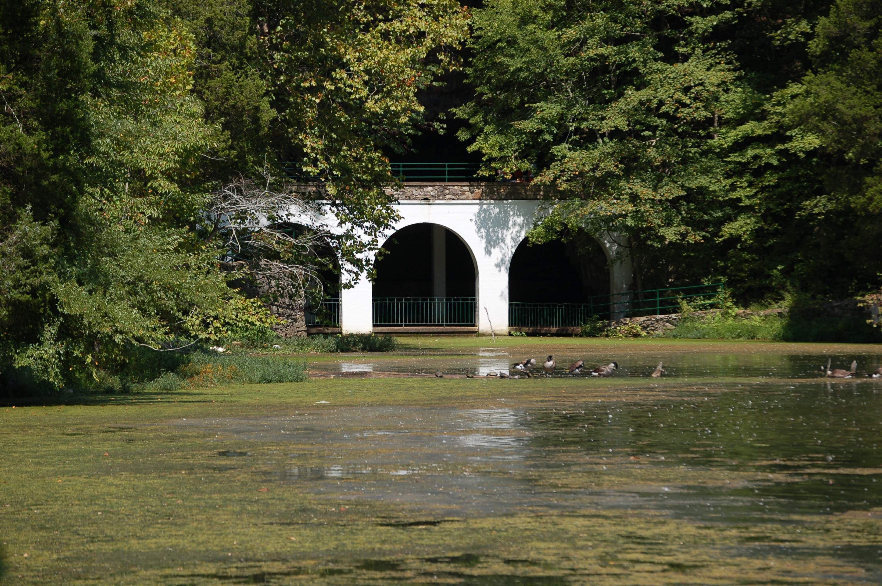 The historic three-arched concrete entrance to Dunbar Cave across Swan Lake